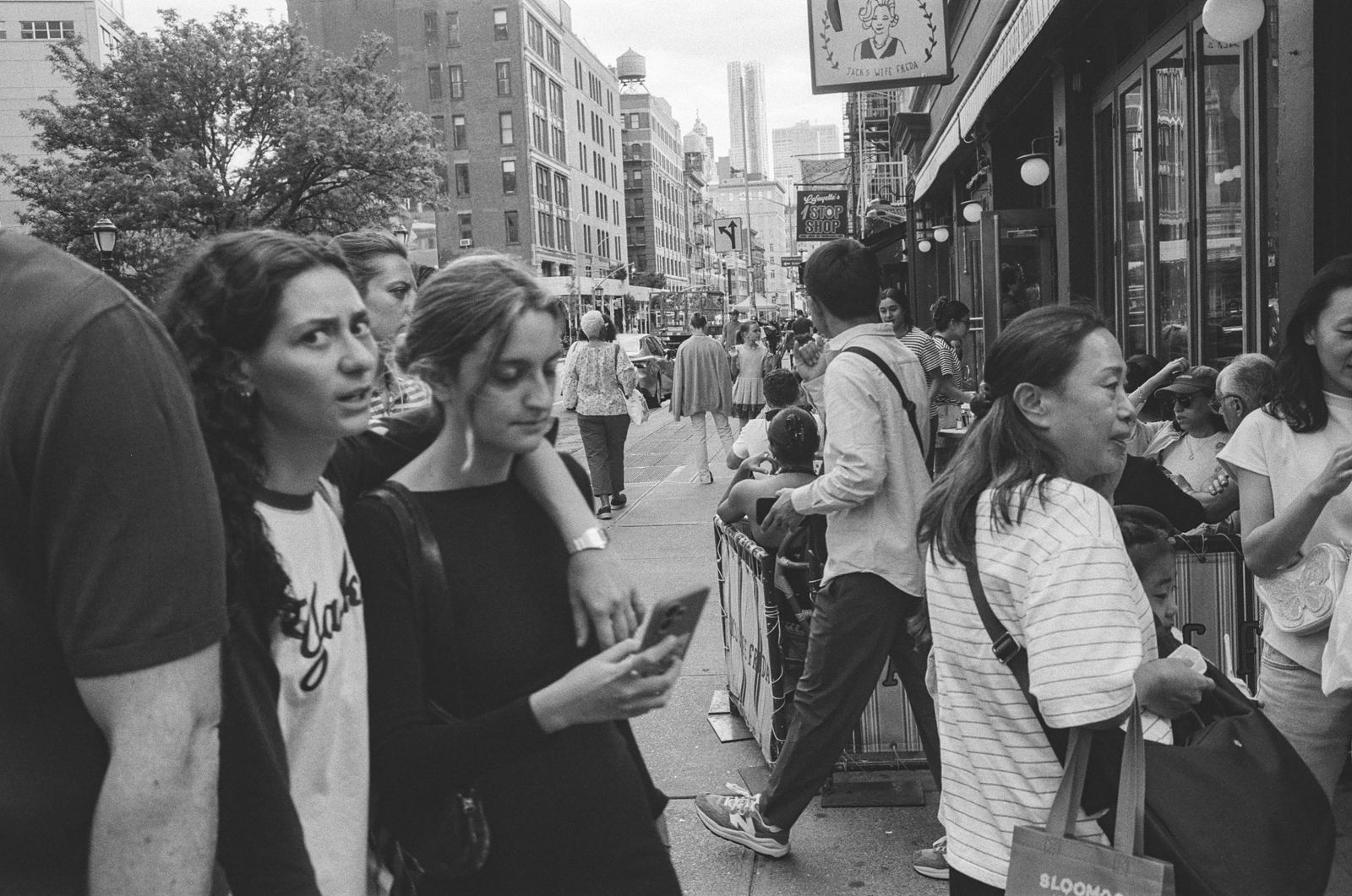 Woman in a sidewalk crowd glancing toward the camera, black-and-white street photograph, New York City