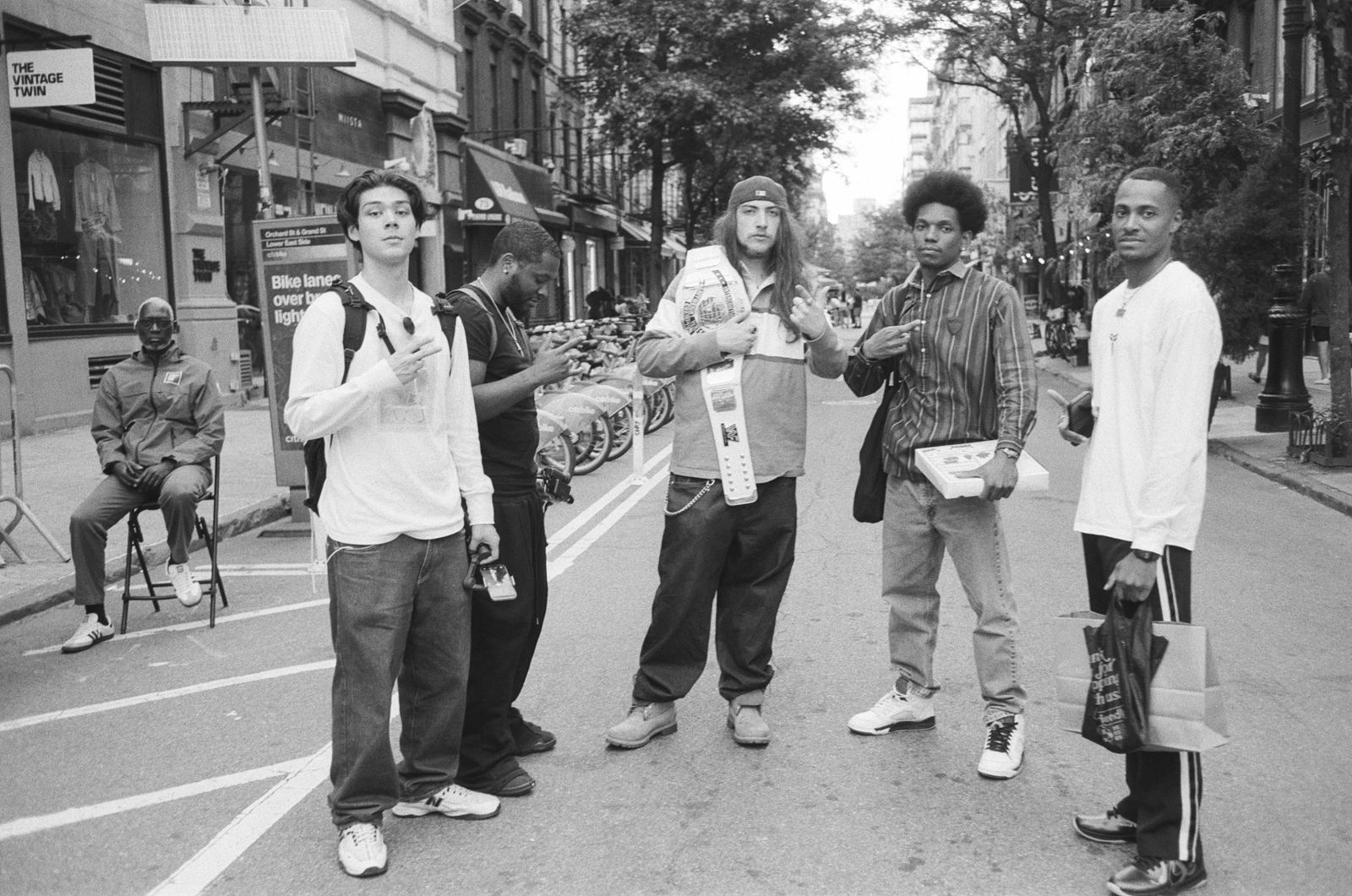 Group of five young men standing in a New York street, all looking at the camera, black-and-white photograph