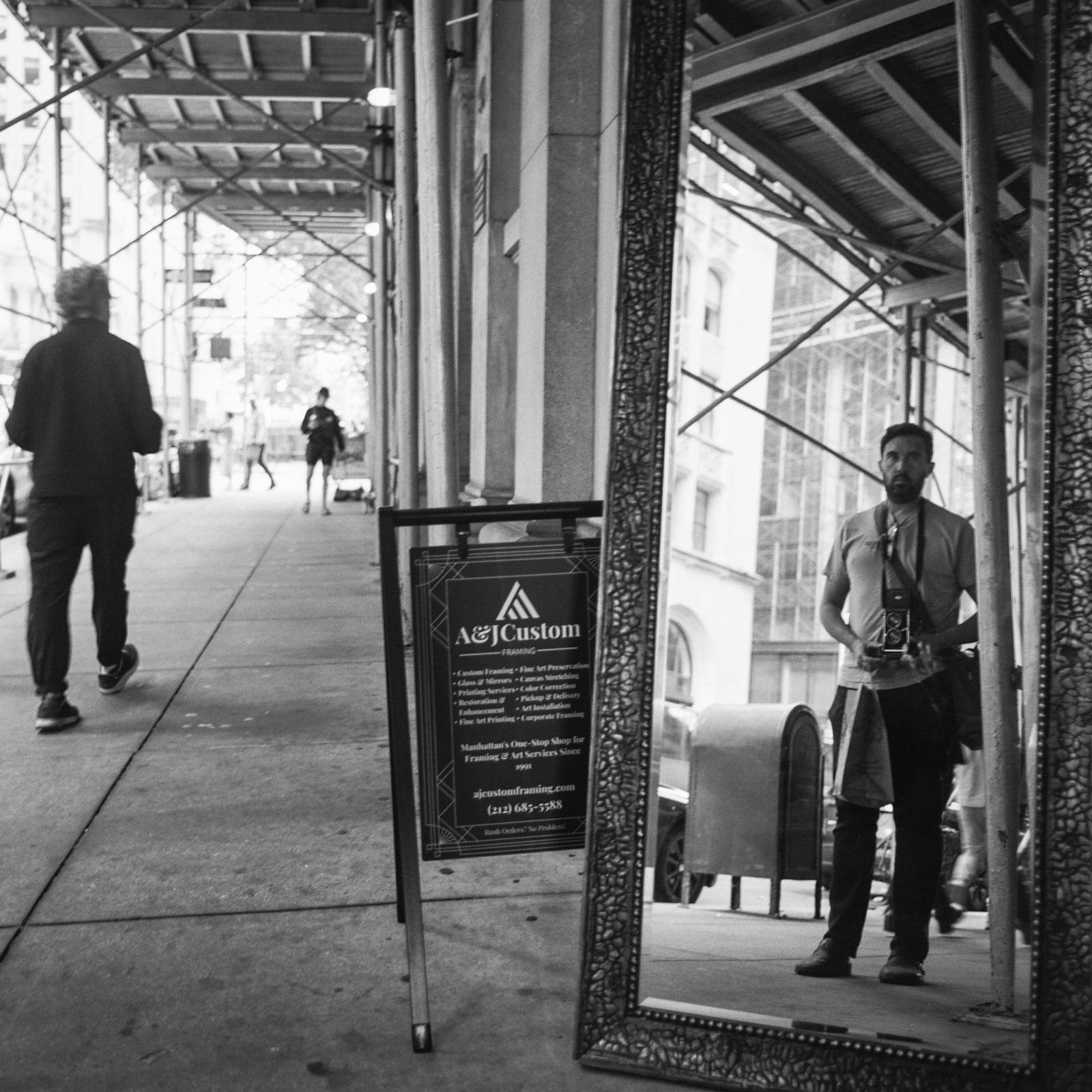 Lee Cohen, NYC photo tour guide, self-portrait with camera in a sidewalk mirror, black-and-white