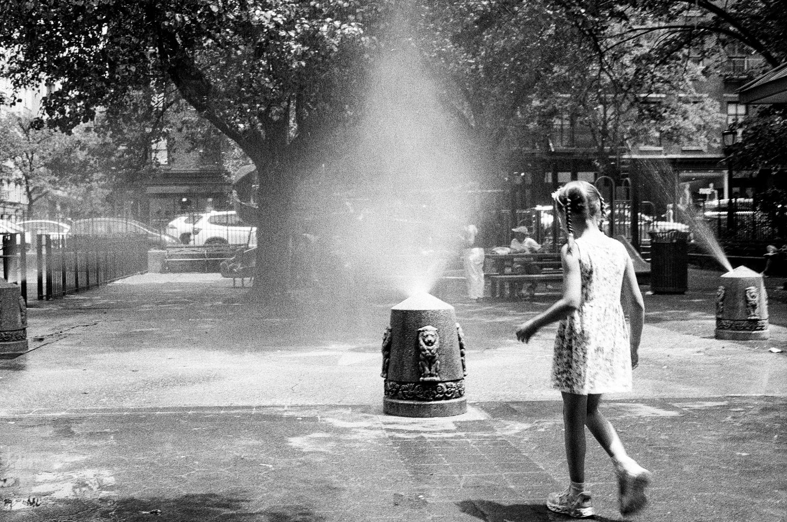 Girl playing in a park sprinkler on a summer day, black-and-white street photograph, New York City