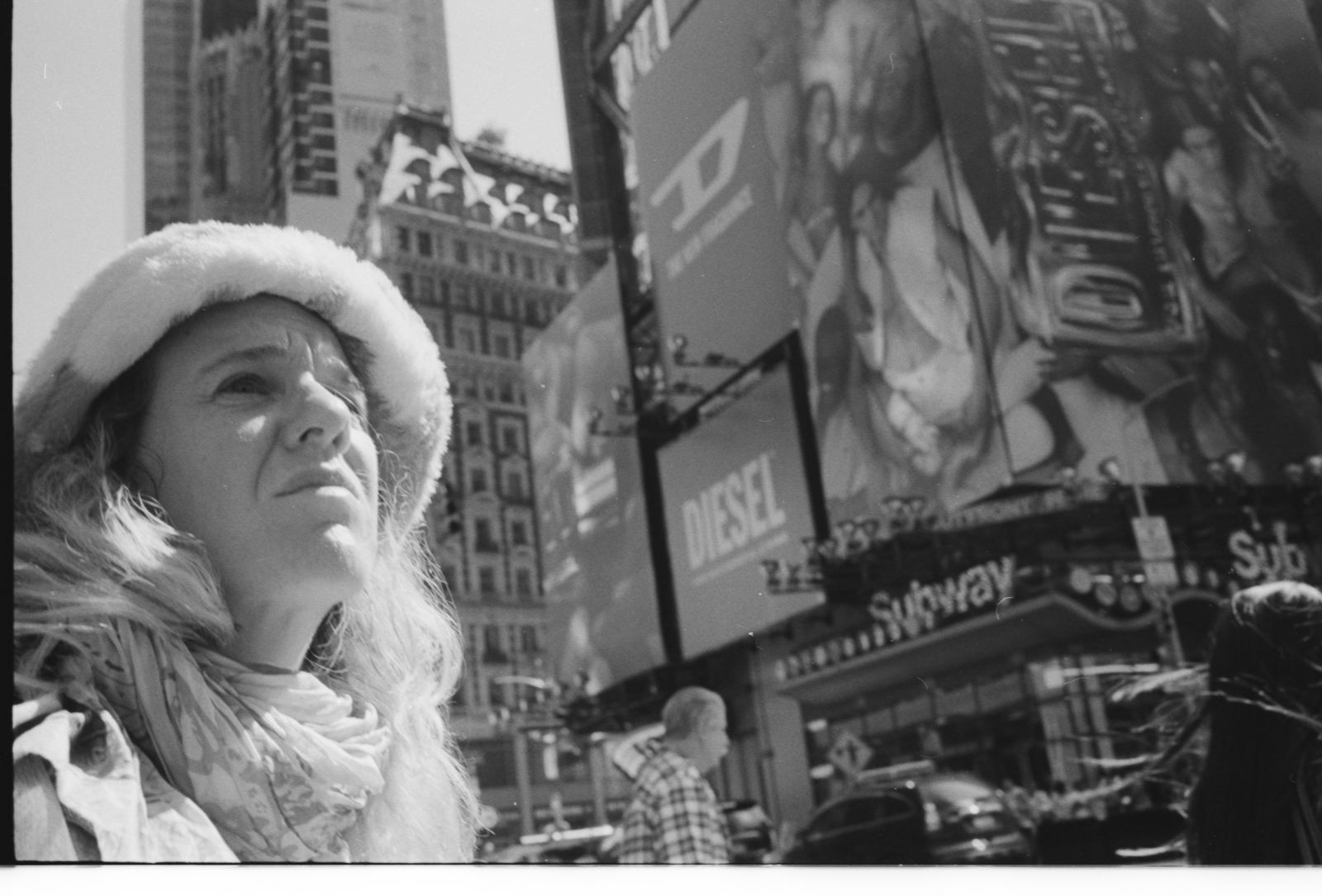 Woman looking up at the billboards of Times Square, black-and-white street photograph, Midtown Manhattan